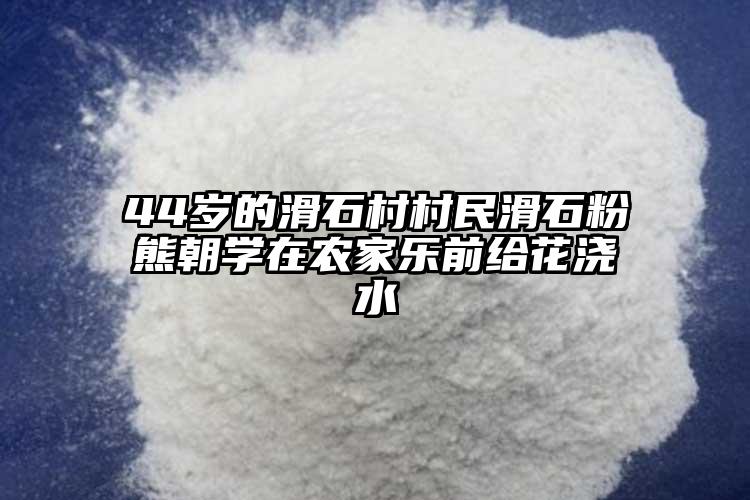 44歲的滑石村村民滑石粉熊朝學(xué)在農(nóng)家樂前給花澆水